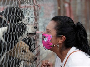 Pet adopter Mary Carmen Arreguin, 41, gestures to dogs behind a fence at San Gregorio animal shelter in El Ajusco, Mexico April 24, 2020.