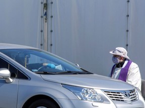 A priest wearing a protective mask gives a "drive-in confession" in front of a church following the coronavirus disease outbreak in Warsaw April 6, 2020. (Adam Stepien/Agencja Gazeta via REUTERS)