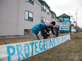 A family places a sign reading "Protect our seniors" outside Residence Herron, a senior's long-term care facility, following a number of deaths since the coronavirus outbreak, in Montreal April 12, 2020. (REUTERS/Christinne Muschi)