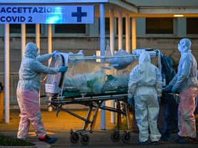 Medical workers in overalls stretch a patient under intensive care into the newly built Columbus Covid 2 temporary hospital to fight the new coronavirus infection, on March 16, 2020, at the Gemelli hospital in Rome.