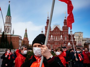 Russian Communist party members and supporters walk towards the Mausoleum of the Soviet state founder and revolutionary leader Vladimir Ilyich Ulyanov aka Lenin to hold a flower-laying ceremony marking the 150th anniversary of his birth on Red Square in Moscow on April 22, 2020, during a strict lockdown in Russia to stop the spread of COVID-19.
