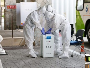 Election officials wearing protective clothing set up a polling station for absentee voting of COVID-19 patients at a quarantine facility in Gyeongju, South Korea on Friday, April 10, 2020.