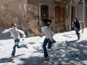 Joan, 45, chases his daughters Ines, 11, and Mar, 9, as they play in the street, in Barcelona, Sunday, April 26, 2020, during a national lockdown to prevent the spread of the COVID-19 disease.
