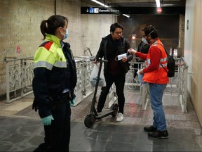 Red Cross volunteers wearing face masks and gloves distribute masks to commuters at the Sants subway station in Barcelona on April 14, 2020. (PAU BARRENA/AFP via Getty Images)