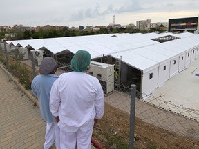 Nurses look at the construction site of a field hospital outside the La Fe Hospital to admit patients suffering from the COVID-19 coronavirus in Valencia on April 5, 2020.