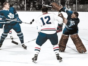 Leafs netminder Terry Sawchuk deflects the puck high while teammate Allan Stanley and Yvan Cournoyer of the Canadiens look on.