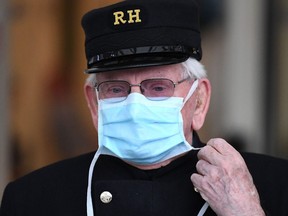 A veteran wearing a Royal Hospital Chelsea hat and a face mask as a precautionary measure against COVID-19 pauses for a minute's silence to honour U.K. key workers, including Britain's NHS staff, health and social care workers, who have died during the coronavirus outbreak outside, the Chelsea and Westminster Hospital in London on Tuesday, April 28, 2020.