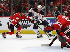 Connor McDavid of the Edmonton Oilers tries to get off a shot against Corey Crawford (50) of the Chicago Blackhawks, but is pressured by Ryan Carpenter at United Center on March 5, 2020, in Chicago.