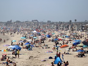People are seen gathering on the beach north of Newport Beach Pier on April 25, 2020 in Newport Beach, California. Dubbed "COVID-19 parties," the Washington state county of Walla Walla report the emergence of an imbecilic initiative where healthy people mingle with infected individuals hoping to contract the virus and then hoping to bounce back from the killer disease.