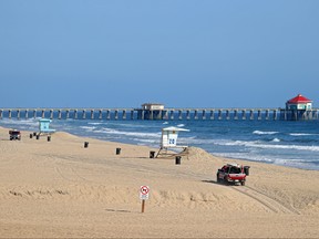 Lifeguards patrol an empty beach in front of the Huntington Beach Pier on May 3, 2020 in Huntington Beach, Calif.