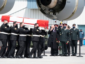 Family members look on as masked pallbearers carry the casket of Sub-Lt. Abbigail Cowbrough during a repatriation ceremony for the six Canadian Armed Forces members killed in a helicopter crash in the Mediterranean, at Canadian Forces Base Trenton, Ont., May 6, 2020.