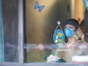 A worker looks out after police officers placed butterfly stickers on windows at Orchard Villa Retirement Residence on Mother's Day, after several residents died of the coronavirus disease (COVID-19) in Pickering, Ont., May 10, 2020.
