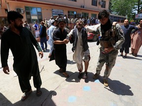 Men carry an injured person to a hospital after a blast during a funeral ceremony in Jalalabad, Afghanistan May 12, 2020.
