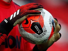 This file photo shows a ball held by Manchester United's David de Gea during the warm-up before a game against Watford F.C. in Manchester, Feb. 23, 2020.