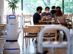 Customers wait at a cafe where a robot that takes orders, makes coffee and brings the drinks straight to customers is being used in Daejeon, South Korea, May 25, 2020.