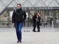 A tourist wearing a protective face mask poses as she stand near The Louvre as as the museum among top tourism landmarks closed their doors on Friday after France's government banned gatherings of more than 100 people to curb the spread of coronavirus in Paris, March 14,2020.