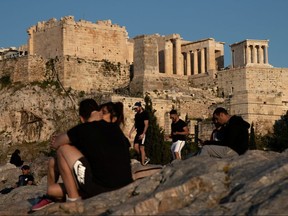 People visit the Areios Pagos hill with the Acropolis' Propylaea seen in the background in Athens, Greece, April 28, 2020.