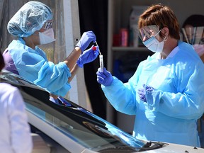In this file photo taken on March 12, 2020 Medical workers at Kaiser Permanente French Campus test a patient for the novel coronavirus, COVID-19, at a drive-thru testing facility in San Francisco, Calif.
