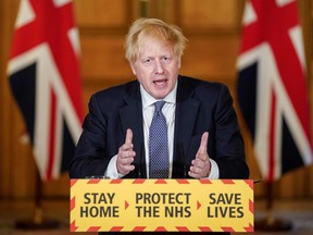 In this file photo taken on April 30, 2020 a handout image released by 10 Downing Street, shows Britain's Prime Minister Boris Johnsons peaking in front of the Government's "Stay Home. Protect the NHS. Save Lives " slogan, during a remote press conference to update the nation on the COVID-19 pandemic, inside 10 Downing Street in central London.