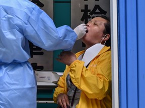 A medical worker takes a swab sample from a woman to be tested for the COVID-19 novel coronavirus in Wuhan, in Chinas central Hubei province on May 13, 2020.