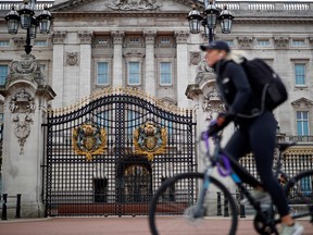 A person cycles past Buckingham Palace in London on May 13, 2020, as people start to return to work after COVID-19 lockdown restrictions were eased.