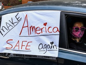 A demonstrator shows a sign with "Make America safe again" written on it while driving past the Governor's Mansion during a drive by protest in Atlanta, on April 24, 2020.