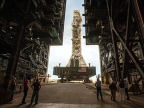NASA employees look on as the Artemis launch tower rolls back from Pad 39B inside Bay 3 of the Vehicle Assembly Building (VAB) at the Kennedy Space Center in preparation for the landfall of Hurricane Dorian, in Cape Canaveral, Fla., Aug. 30, 2019.