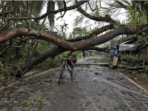 A man walks with his bicycle under an uprooted tree after Cyclone Amphan made its landfall, in South 24 Parganas district, in the eastern state of West Bengal, India, May 21, 2020.