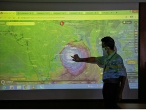 A scientist at India Meteorological Department Earth System Science Organisation, points to a section of the screen showing the position of the Cyclone Amphan to media people inside his office in Kolkata, India, May 19, 2020.