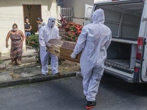 The SOS Funeral team members carry the coffin with the body of Lucia Rodrigues dos Santos, 60 years old, whose death is not determined yet, at Zumbi dos Palmares neighbourhood, in Manaus, Brazil, Sunday, May 24, 2020.