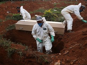 Gravediggers wearing protective suits prepare to bury the coffin of a person who died from COVID-19 during a ceremony with no relatives, at Vila Formosa cemetery, Brazil's biggest cemetery, in Sao Paulo, Friday, May 22, 2020.