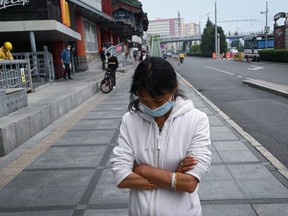 A woman wearing a face mask walks along a road in Beijing on May 7, 2020.