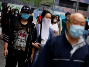 People wearing face masks walk in a shopping district, following the COVID-19 outbreak, in Beijing, China, on Monday, May 4, 2020.