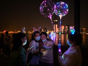 Women wearing face masks take a selfie in Hankou Park in Wuhan, in China's central Hubei province on May 22, 2020.