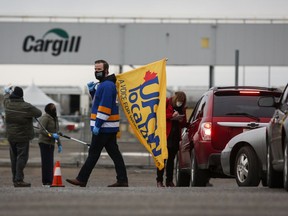 A union representative greets workers returning to the Cargill beef processing plant in High River, Alta., that was closed for two weeks because of COVID-19 Monday, May 4, 2020. Prime Minister Justin Trudeau announced Tuesday more than $77 million to help keep workers in the food processing industry safe.