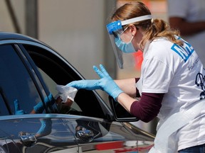 A medical worker takes a swab to test for COVID-19 from a visitor to a drive-in testing facility at the Chessington World of Adventures Resort, in Chessington, May 2, 2020.