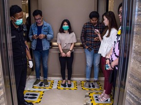 People stand on designated areas to ensure social distancing inside an elevator at a shopping mall during the COVID-19 pandemic in Surabaya, Indonesia on March 19, 2020.