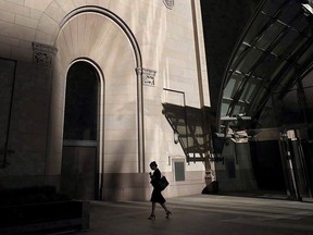 A woman walks through Toronto's financial district on July 30, 2018. With women bearing the brunt of the COVID-19 pandemic, federal officials are trying to figure out how recovery efforts can help get women back to work, earning more money and securing more stable jobs.