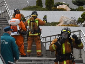 Emergencies personnel wearing protective gear spray disinfectant on colleagues at the site of a fire at the Saint George hospital in Saint Petersburg on May 12, 2020.