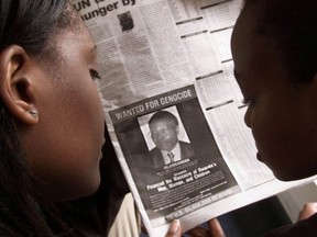 Readers look at a newspaper June 12, 2002 in Nairobi carrying the photograph of Rwandan Felicien Kabuga wanted by the United States.