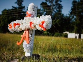A white and orange cross with an "A" on it stands in the ground at the entrance of the Satilla Shores neighbourhood where Ahmaud Arbery was shot in Brunswick, Georgia, May 8, 2020.