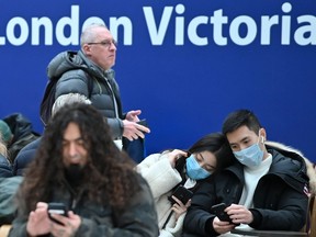 Travellers wear protective face masks as they wait on the concourse at London Victoria train station in central London on March 3, 2020.