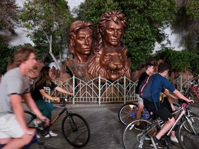 Cyclists stop by candles lit for Roy Horn next to the bronze busts of Horn and his magician partner Siegfried Fischbacher outside The Mirage Hotel & Casino on the Las Vegas Strip after news of Horn's death at the age of 75 from complications from the coronavirus on May 8, 2020 in Las Vegas, Nevada.