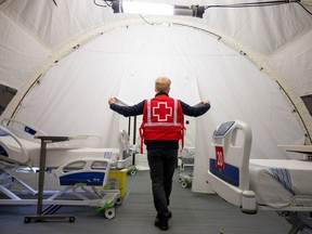 A volunteer with the Red Cross shows a doorway between beds in a mobile hospital set up in partnership with the Canadian Red Cross in the Jacques-Lemaire Arena to help care for patients with the coronavirus disease (COVID-19) from long-term centres (CHSLDs), in Montreal, Quebec, Canada April 26, 2020.