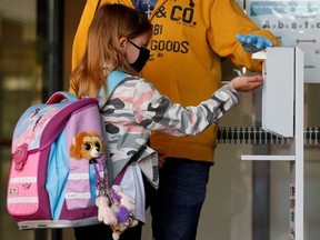 A child wearing a protective face mask disinfects hands as she arrives at a primary school, while Austrian schools reopen for pupils aged roughly six to 14, during the global coronavirus disease (COVID-19) outbreak, in Brunn am Gebirge, Austria May 18, 2020.