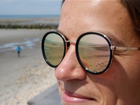 A beach is reflected in a woman's sunglasses after France reopened its beaches to the public as it softens its strict lockdown rules during the outbreak of the coronavirus disease (COVID-19), in Wimereux, France May 16, 2020.
