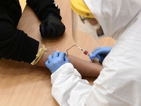 A medical worker takes a blood sample from a man to test for the coronavirus disease (COVID-19) at a converted gym in Cisliano, near Milan, Italy, April 21, 2020.