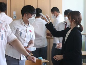 A high school teacher checks body temperature of a student at a classroom following the global outbreak of the coronavirus disease (COVID-19), in Gimhae, South Korea, May 20, 2020.