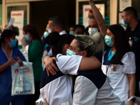 Medical staff from Fundacion Jimenez Diaz hospital embrace each other while people applaud from their balconies in support for healthcare workers, as it is expected to be the last day of applauses, amid the coronavirus disease (COVID-19) outbreak, in Madrid, Spain, May 17, 2020.