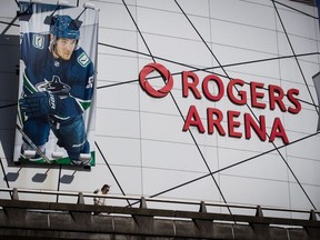 A woman walks past a large photo of Vancouver Canucks captain Bo Horvat outside Rogers Arena, home to the NHL team, in Vancouver, on Thursday, March 12, 2020.